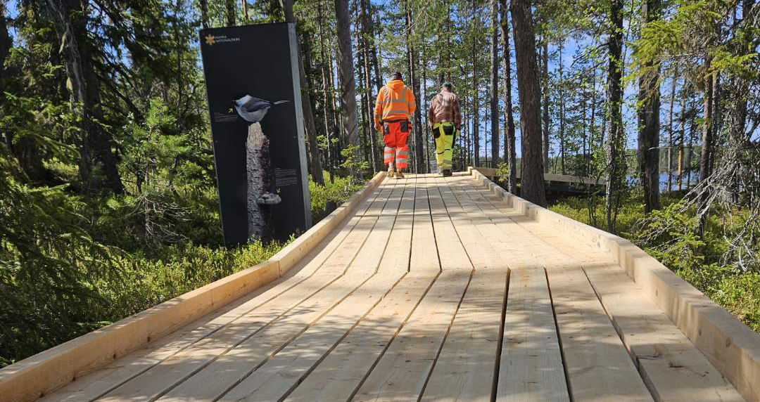 två personer promenerar på en trätrottoar