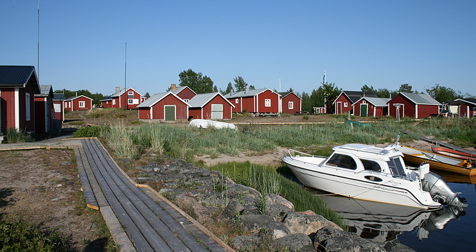 Röda sjöstugor och en motorbåt vid en brygga.
