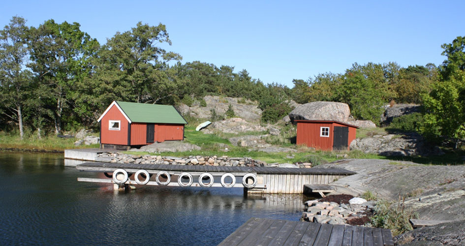 Bryggan på Hamnskär med röda små stugor i bakgrunden.