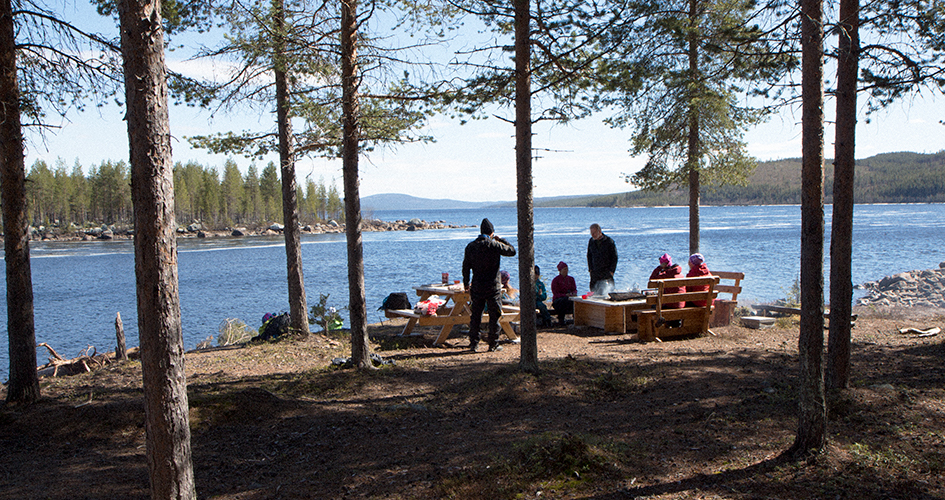 Ett sällskap av människor rastar vid rastplats vid en sjö.