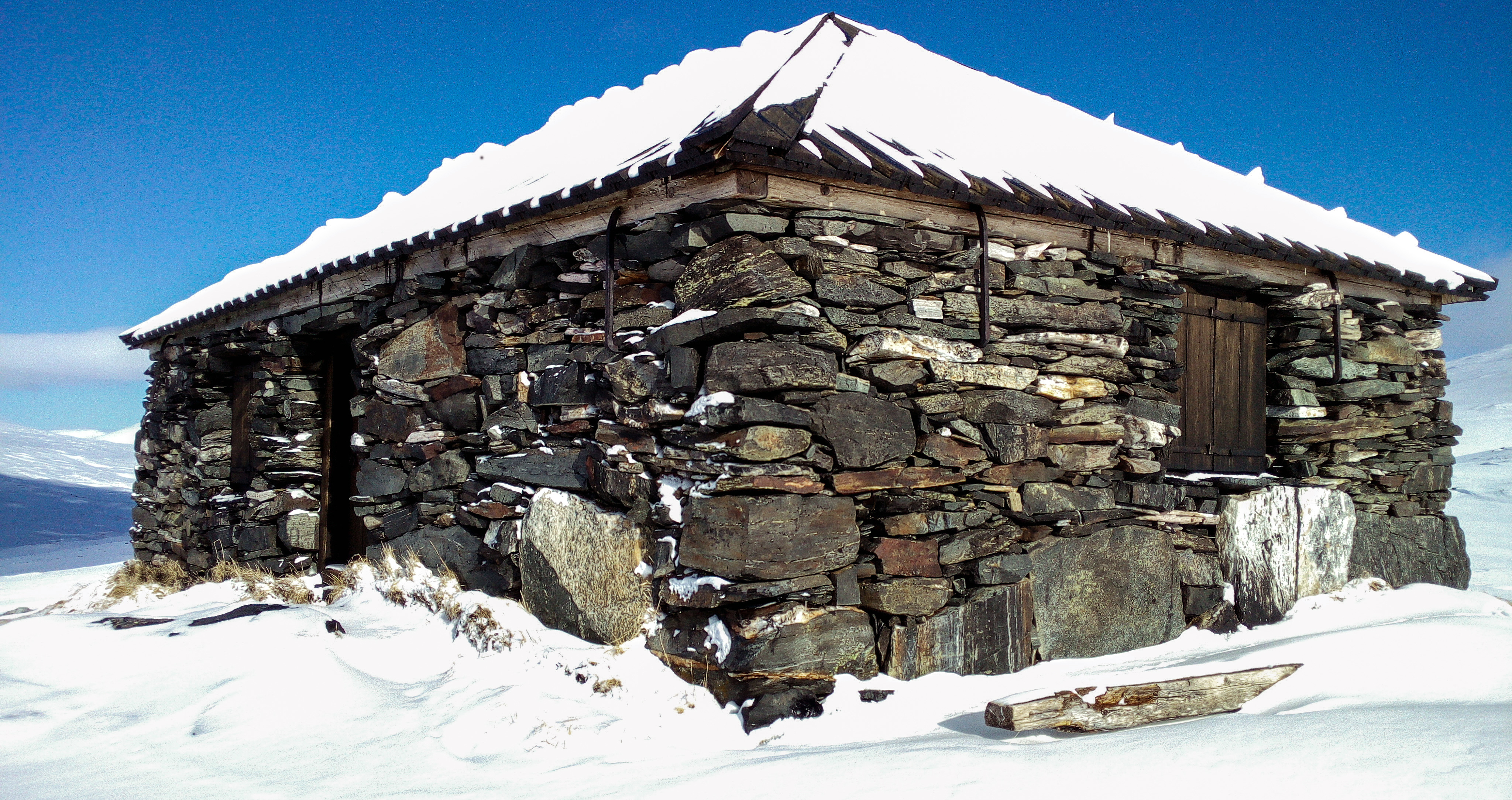 Alggavarre kapell. Ett stenhus står i snöbeklätt snölandskap. 