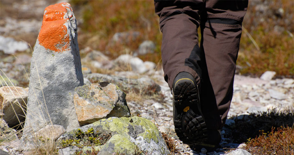 Närbild av en vandrares fötter som går på en stenklädd vandringsled.
