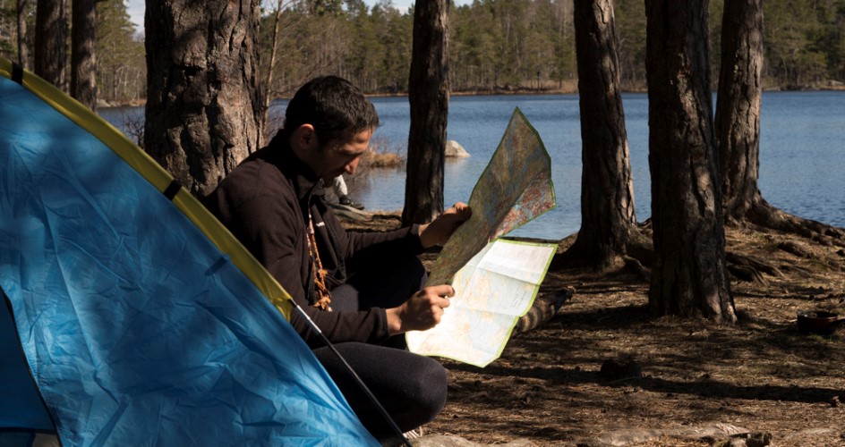 En man sitter vid en rastplats med en karta i handen.